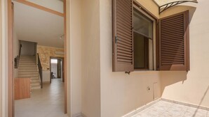 A spacious interior with a tiled floor, a staircase leading to another room, and a window with wooden shutters. - 3494 Vico Roca by Barbarhouse (Melendugno)