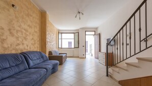 A spacious living area with a blue sofa, a brown armchair, and a staircase with a metal railing. - 3494 Vico Roca by Barbarhouse (Melendugno)
