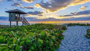 A lifeguard tower on a beach with a clear view of the sunset and dense vegetation in the foreground. - Villa Nicole: 4-min walk to beach, off of Atlantic (Delray Beach)