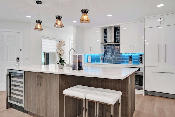 A modern kitchen with a central island, white cabinetry, and pendant lighting.