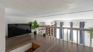 A spacious living area with a flat-screen TV, wooden flooring, a staircase, and a balcony with blue curtains. - Enjoy a stay in the Vittoria home just 15 minutes from Milan Cathedral. (Milano)