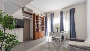 A modern living room with a sofa, a dining table with chairs, a bookshelf, and a TV mounted on the wall. - Enjoy a stay in the Vittoria home just 15 minutes from Milan Cathedral. (Milano)