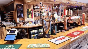 A bar area with a variety of liquor bottles, a beer tap, and a digital payment terminal. - Oddfellows Hotel Bar & Restaurant (Goole)
