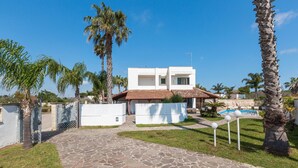 A modern house with a stone pathway leading to a pool area, surrounded by palm trees and a clear blue sky. - 3542 Villa Beach by Barbarhouse (Melendugno)