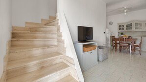 A staircase leading to a dining area with a television on a stand, a kitchen with cabinets, and a ceiling fan. - 3542 Villa Beach by Barbarhouse (Melendugno)