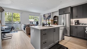 Een moderne keuken met grijze kastjes, roestvrijstalen apparatuur en een groot eiland.