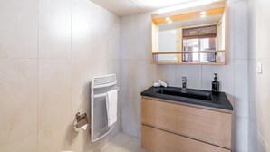 Een moderne badkamer met een zwarte wastafel, een houten wastafelmeubel en een spiegel erboven.