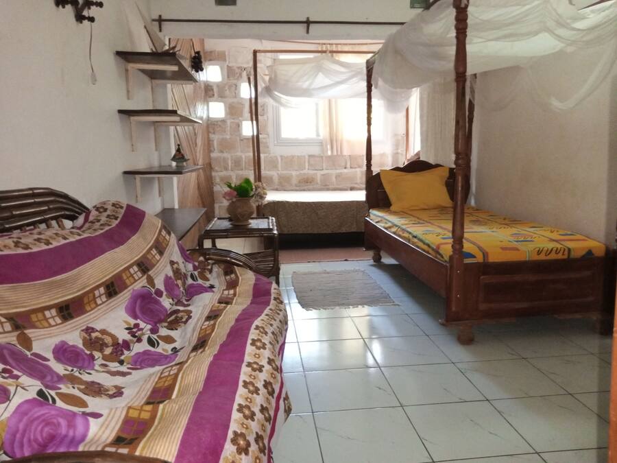 A room with a bed, a sofa, a small table, and a window.