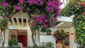 A modern building with a covered outdoor seating area, surrounded by lush greenery and flowering plants. - Villa Vista Hermosa Huatulco (Santa María Huatulco)