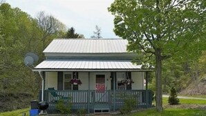 Et toetagers hus med ståltag, en veranda med blomsterkurve og en parabol.