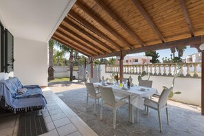 Eine Terrasse mit überdachter Sitzgruppe, einem Esstisch und Stühlen.