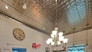 Une cuisine spacieuse avec un îlot central en bois, un lustre et une grande fenêtre offrant une belle vue.