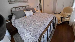 Une chambre à coucher comprenant un lit, une chaise, une armoire et une table de chevet.