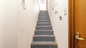 A staircase with carpeted steps leading to a door with a brass handle.