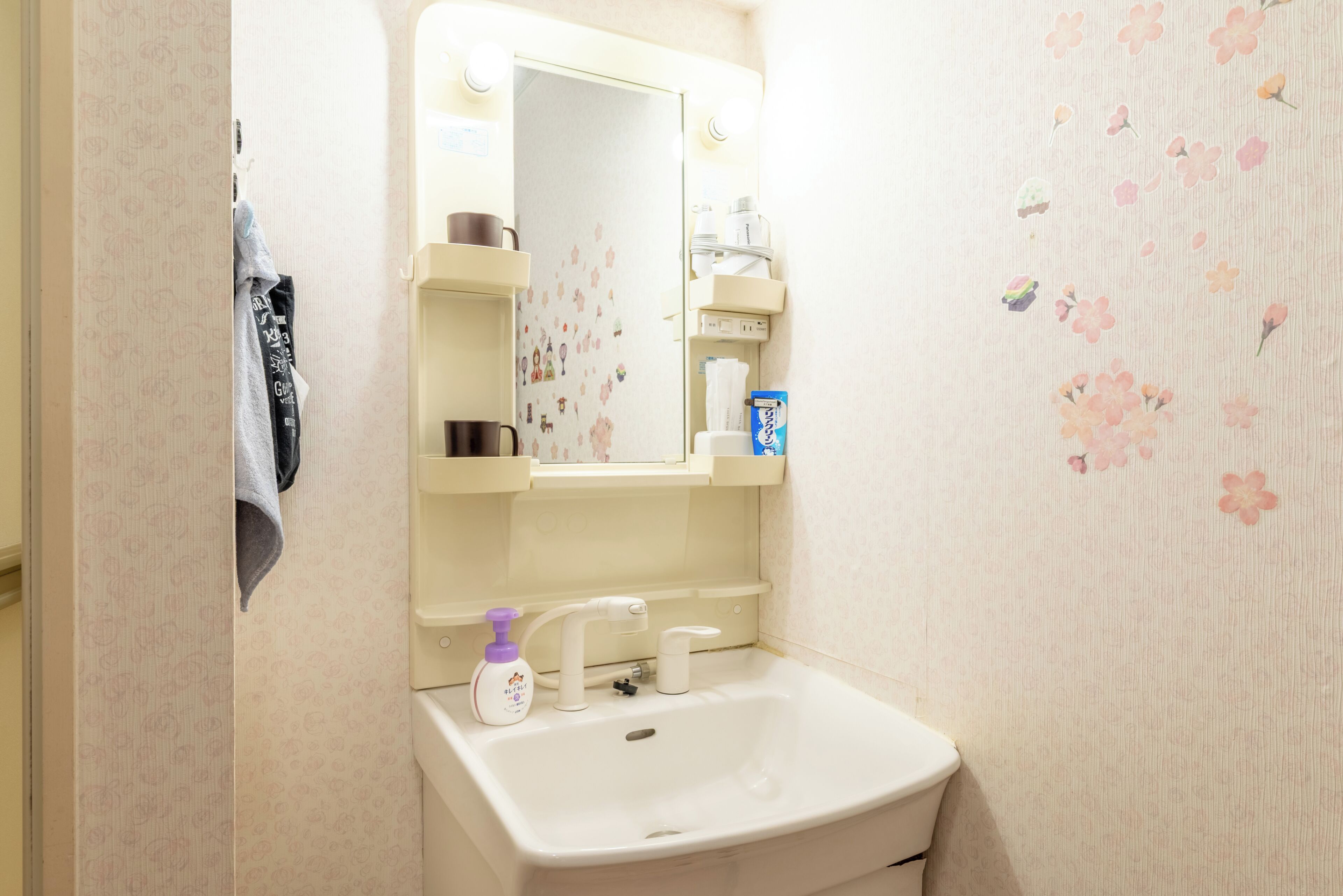 Un bagno con lavandino bianco, uno specchio e un portascopevoli.
