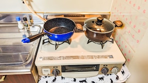 A kitchen with a stove, two pots, a sink, and a faucet. - DoumoTengachaya (Osaka)