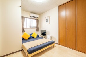 A bedroom with a bed, a television, an air conditioning unit, a wardrobe, and a window with curtains. - DoumoTengachaya (Osaka)