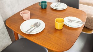 A small wooden table with four plates, two forks, two spoons, and three mugs.