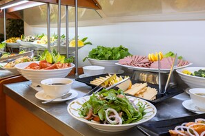Ein reichhaltiges Buffet mit verschiedenen Speisen, darunter Salate, Fleisch und Früchte.