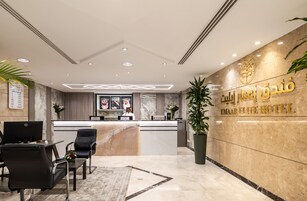 Zona de recepción de un hotel con un mostrador de mármol, una computadora y asientos.