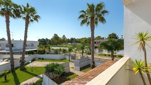 Zona residencial con palmeras, un edificio blanco y un camino pavimentado.