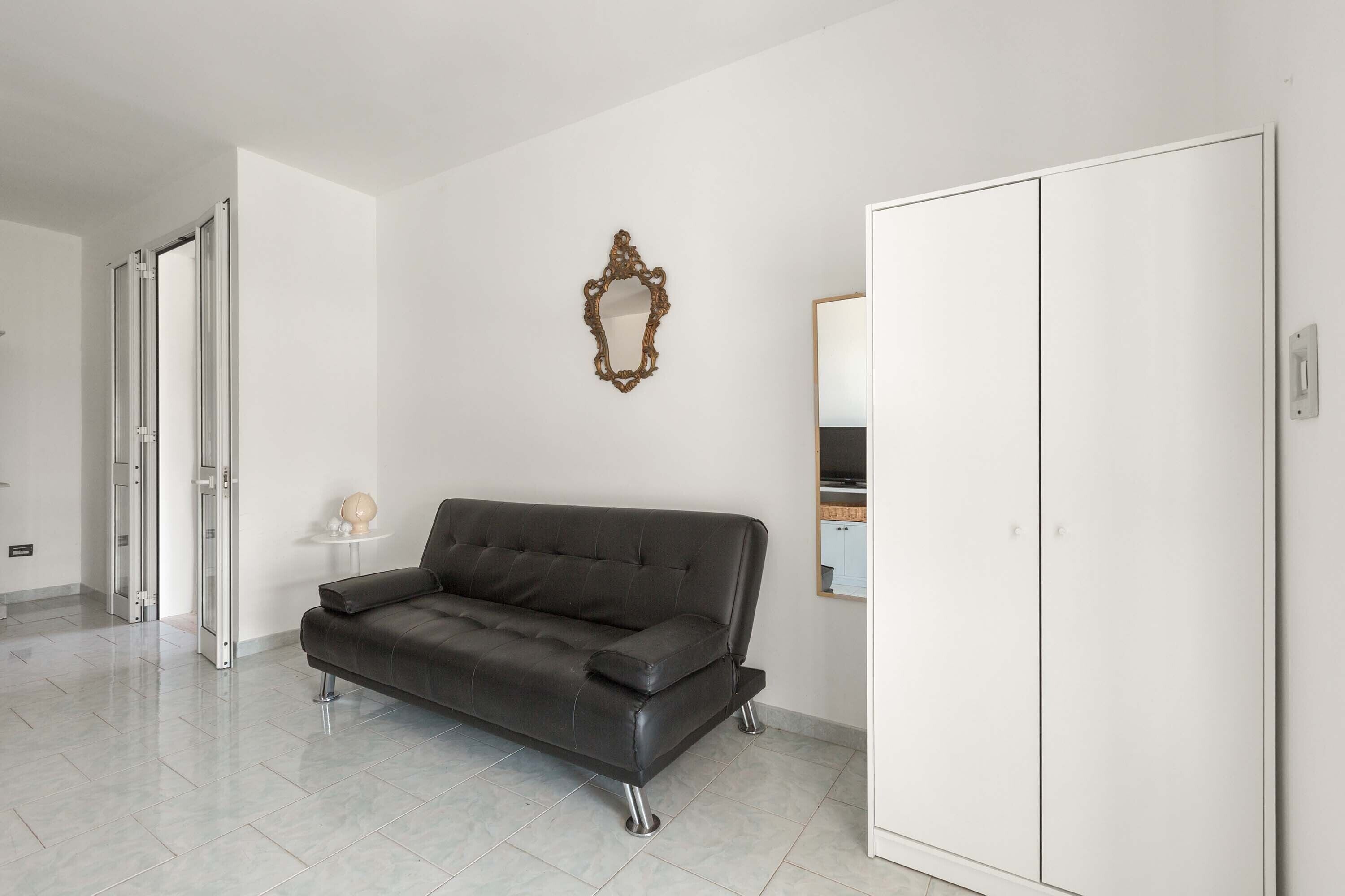 Ein modernes Wohnzimmer mit einem dunkelbraunen Ledersofa, einem weißen Kleiderschrank und einem dekorativen Spiegel an der Wand.