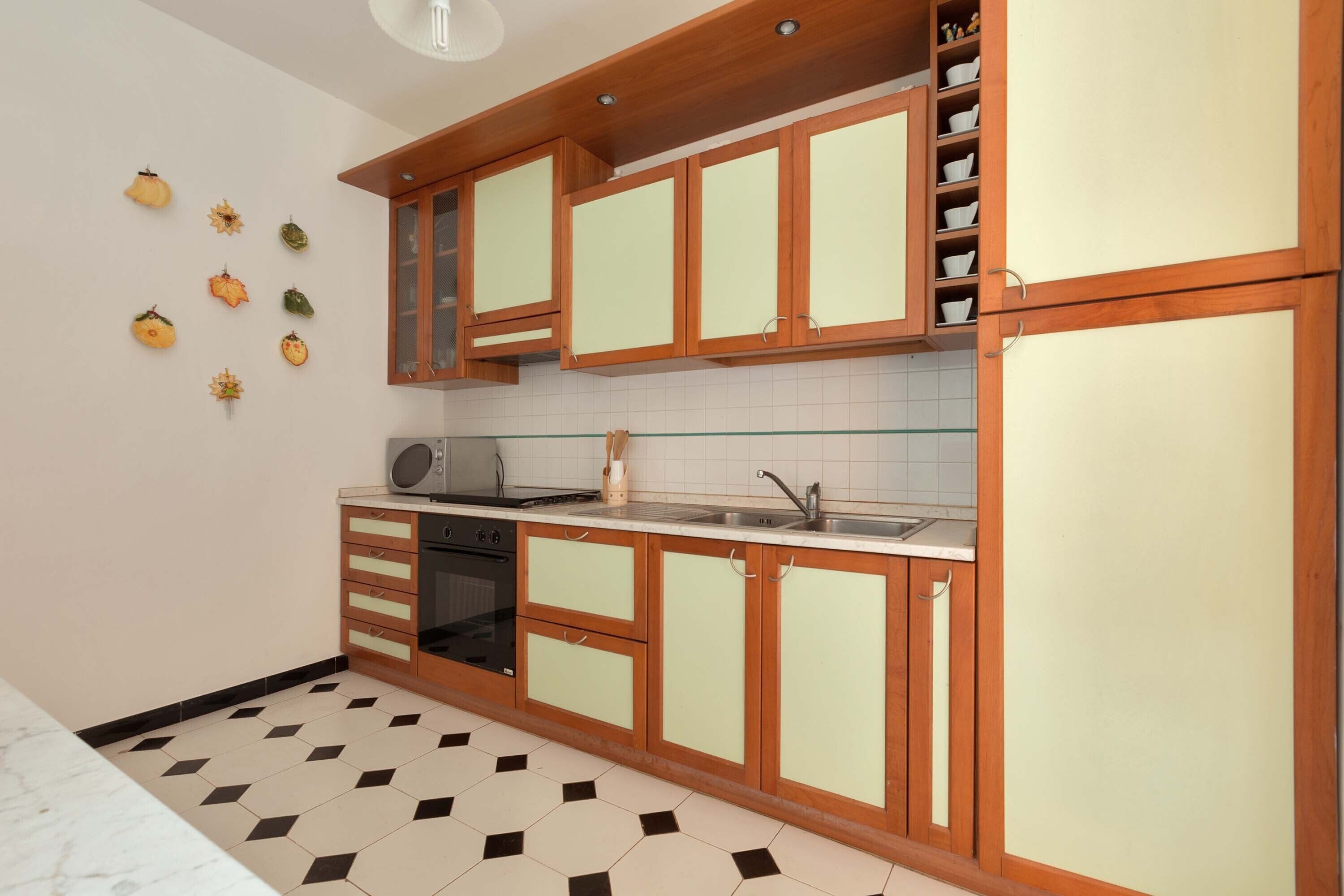 A kitchen with wooden cabinets, a microwave, and a sink.