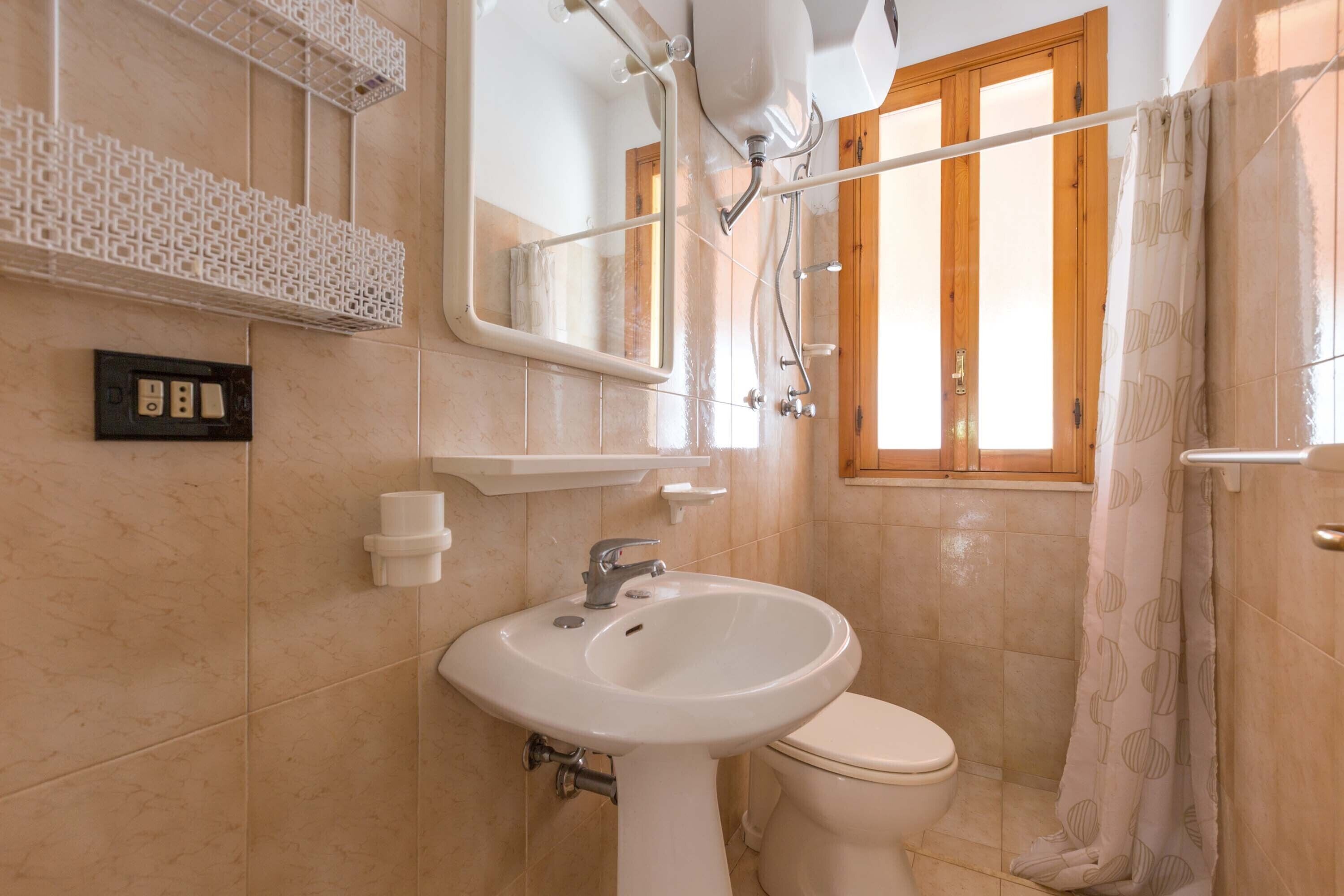 A bathroom with a white sink, a toilet, a mirror, and a shower curtain.