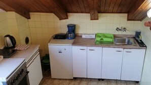A compact kitchen with a stove, refrigerator, coffee maker, and sink. - Cozy Seafront Retreat in Cavtat (Konavle)