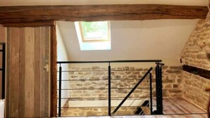 A room with a sloped ceiling, a stone wall, and a wooden door. - Maison Chaleureuse Avec SPA (Savigny-sous-Mâlain)