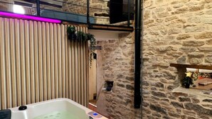 A spa area with a stone wall, wooden slats, and a hot tub. - Maison Chaleureuse Avec SPA (Savigny-sous-Mâlain)