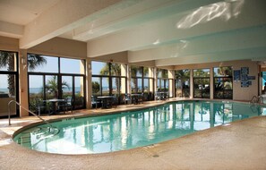 An indoor swimming pool with clear views of the ocean through large windows.