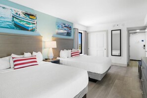 Une chambre d’hôtel avec deux lits, une grande fenêtre et un tableau représentant des bateaux accroché au mur.