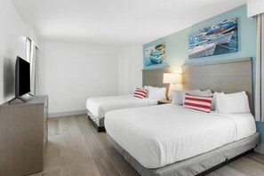 Quarto de hotel com duas camas, televisão e obras de arte na parede.