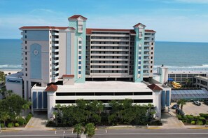 A multi-story hotel with a central atrium, a parking garage, and a view of the ocean.