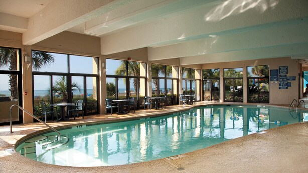 An indoor swimming pool with clear views of the ocean through large windows.