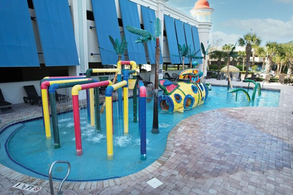 A swimming pool with colorful water slides and a palm tree.