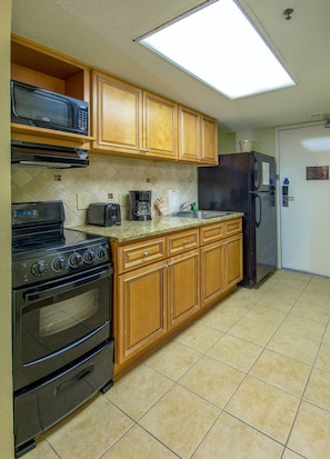 Una cocina con armarios de madera, un microondas, una estufa, un refrigerador y un tostador.