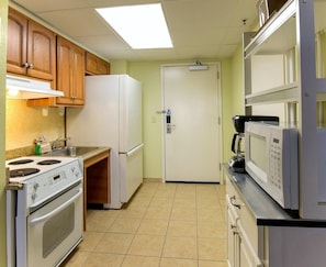 Cocina compacta equipada con estufa, horno, refrigerador, microondas y cafetera.