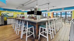 Un espace bar doté d’un long comptoir, de nombreux tabourets et d’un éclairage suspendu.