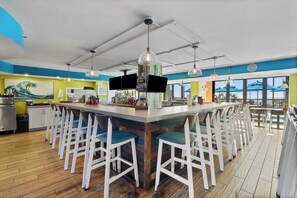 A bar area with a long counter, multiple stools, and overhead lighting.