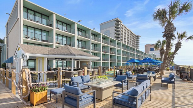 Ein Hotel mit einer Terrassenanlage, Sitzgelegenheiten im Freien und einem Pool.