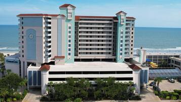 A multi-story hotel with a central atrium, a parking garage, and a view of the ocean.