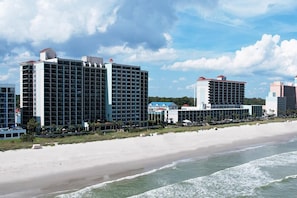 A beachfront hotel with multiple high-rise buildings, a sandy beach, and ocean waves.