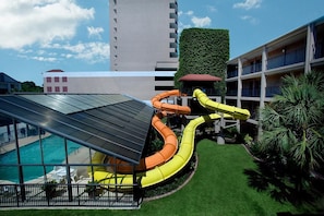 A rooftop pool area with a water slide, surrounded by a well-maintained lawn and a building with balconies. - Seaview Getaway 2 Queens, Ocean Balcony (Myrtle Beach)