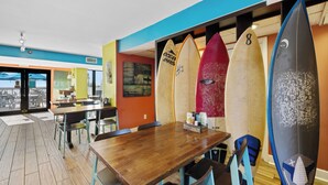 L’intérieur d’un restaurant, avec des planches de surf accrochées au mur, des tables et des chaises en bois.