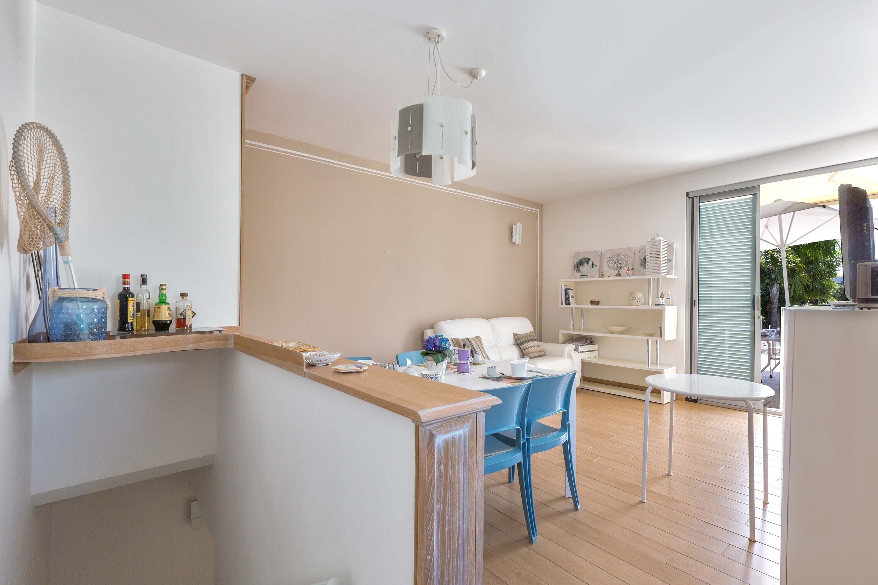 Eine moderne Küche mit Holzarbeitsplatte, ein Essbereich mit blauen Stühlen und ein weißes Sofa.