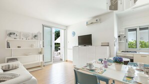 Una cucina moderna con mobili bianchi, un tavolo da pranzo con sedie e una TV montata sopra il bancone.