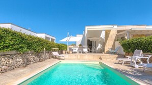 Una piscina con acqua cristallina blu, circondata da confortevoli lettini e ombrelloni.
