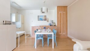 Una cucina moderna con mobili bianchi, un tavolo da pranzo con sedie blu e una porta in legno.